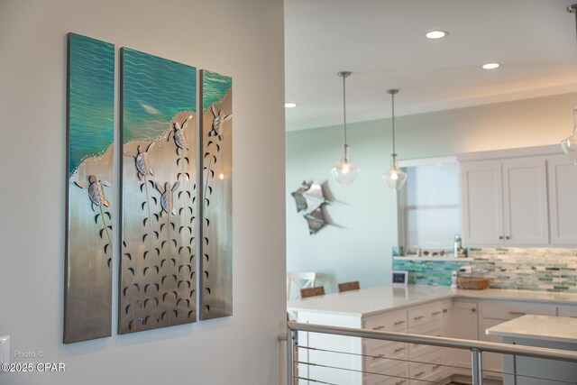 kitchen with tasteful backsplash, white cabinets, and hanging light fixtures