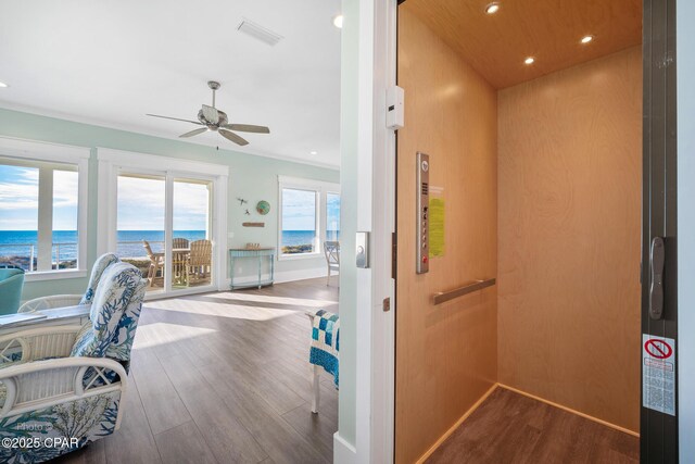 interior space with visible vents, elevator, dark wood-style floors, a water view, and recessed lighting