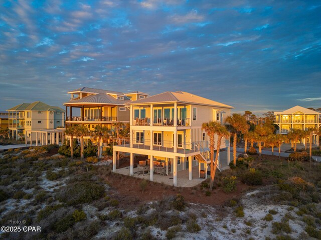 back of house featuring stairs, metal roof, a patio area, and a balcony