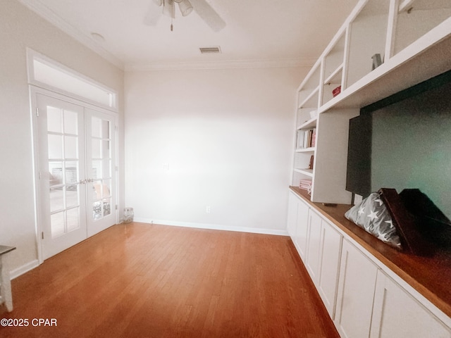 empty room featuring crown molding, wood-type flooring, ceiling fan, and french doors