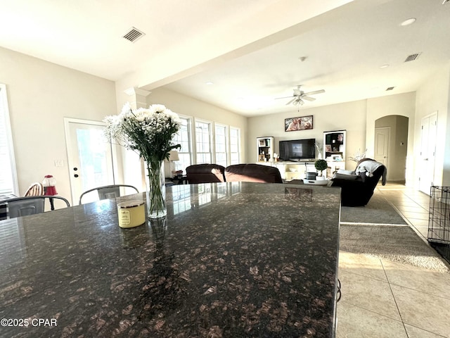 kitchen featuring dark stone countertops, a kitchen breakfast bar, ceiling fan, and light tile patterned flooring