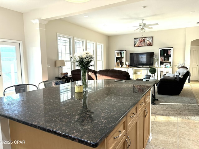 kitchen featuring a center island, dark stone countertops, ceiling fan, and light tile patterned floors