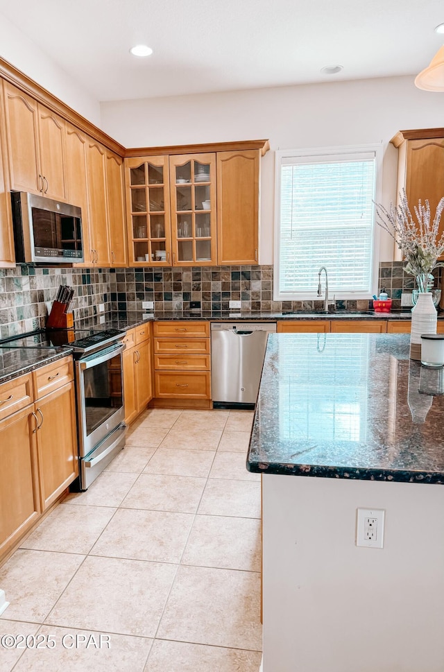 kitchen featuring light tile patterned flooring, appliances with stainless steel finishes, backsplash, and dark stone countertops