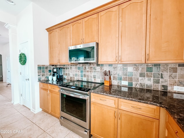 kitchen featuring stainless steel appliances, backsplash, and dark stone counters