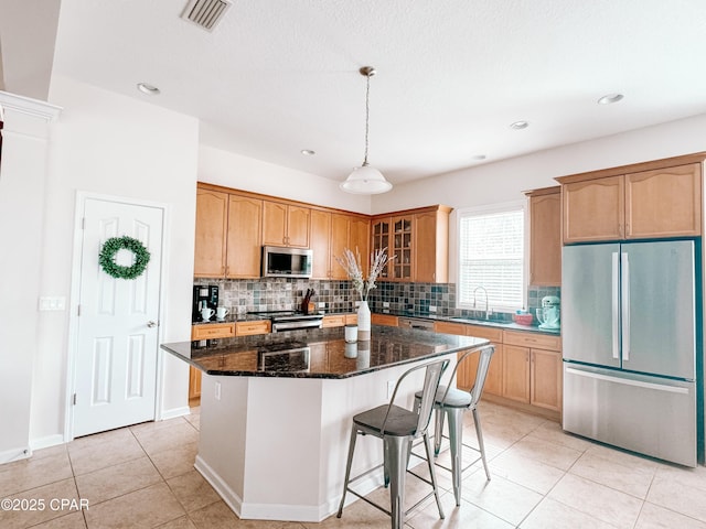 kitchen with sink, a center island, appliances with stainless steel finishes, dark stone counters, and decorative backsplash