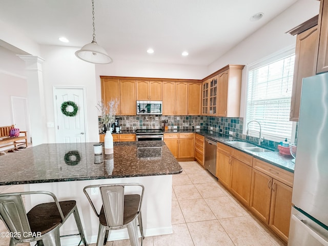 kitchen featuring sink, stainless steel appliances, hanging light fixtures, and a center island