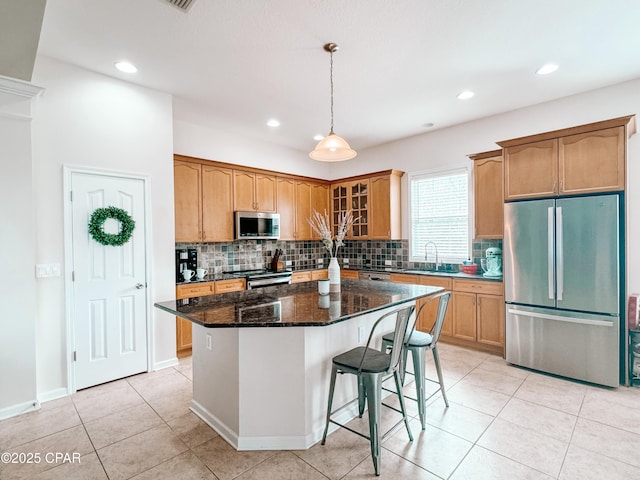 kitchen featuring a kitchen island, sink, dark stone countertops, decorative backsplash, and stainless steel appliances