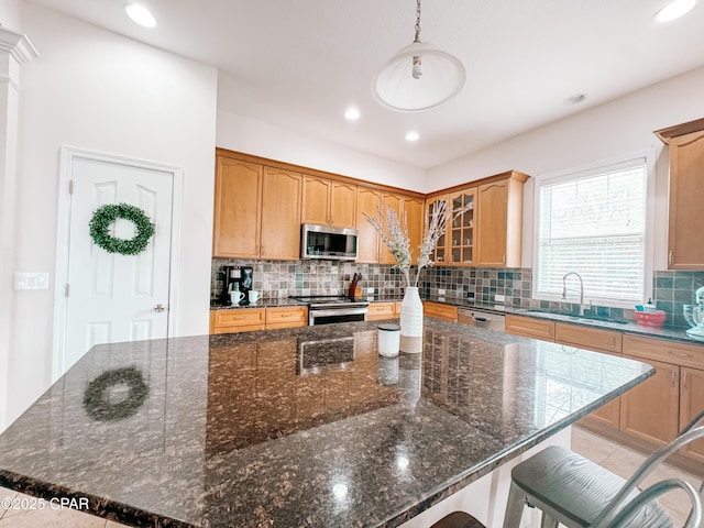 kitchen featuring sink, a center island, hanging light fixtures, dark stone countertops, and stainless steel appliances