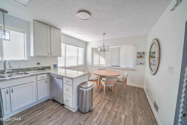 kitchen with decorative light fixtures, stainless steel dishwasher, kitchen peninsula, sink, and white cabinets