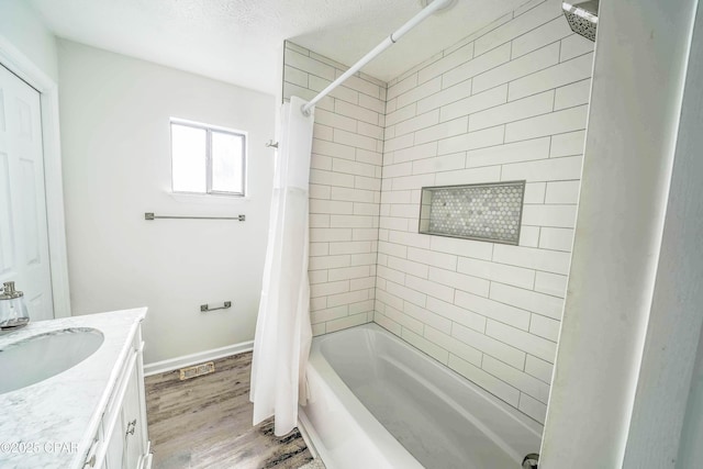 bathroom with hardwood / wood-style flooring, a textured ceiling, shower / bath combo with shower curtain, and vanity