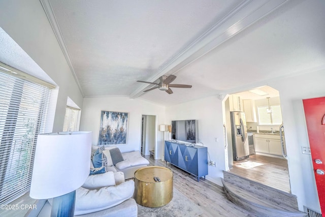 living room with ceiling fan, vaulted ceiling with beams, light wood-type flooring, and a wealth of natural light