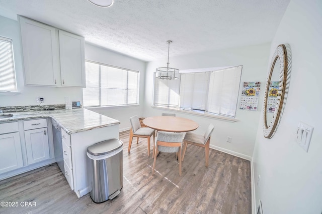 kitchen with a notable chandelier, pendant lighting, kitchen peninsula, hardwood / wood-style flooring, and a textured ceiling