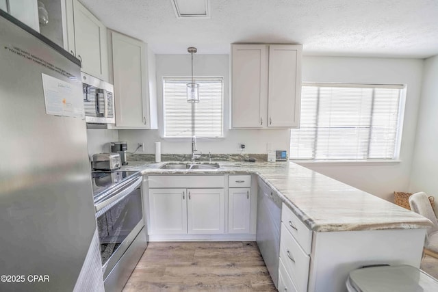 kitchen with stainless steel appliances, pendant lighting, and white cabinets