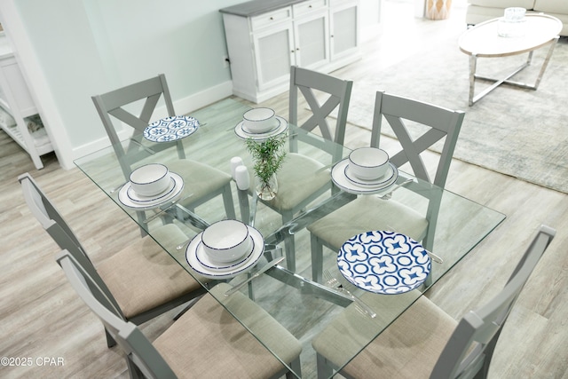 dining space featuring baseboards and light wood-style floors