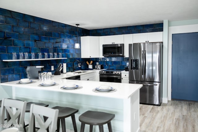 kitchen featuring light countertops, tasteful backsplash, stainless steel appliances, a sink, and a peninsula