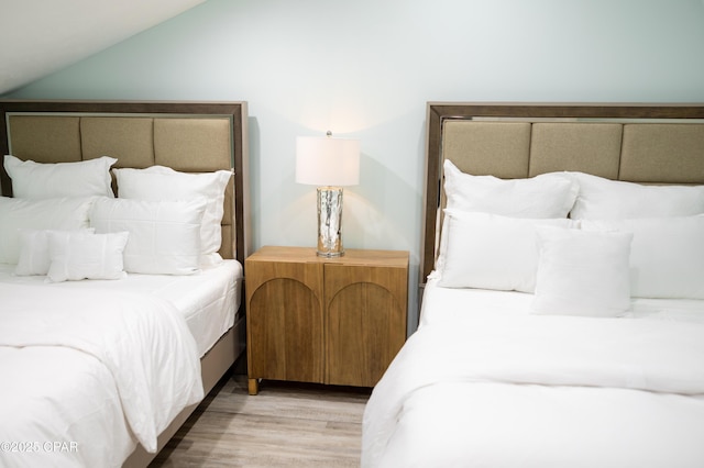 bedroom featuring vaulted ceiling and light wood-type flooring