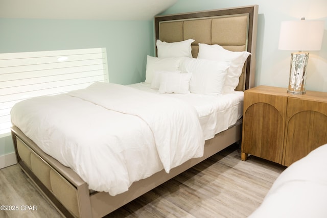bedroom with light wood-style floors and lofted ceiling