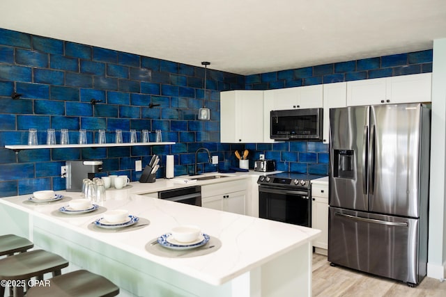 kitchen with stainless steel appliances, light stone countertops, backsplash, a sink, and a peninsula