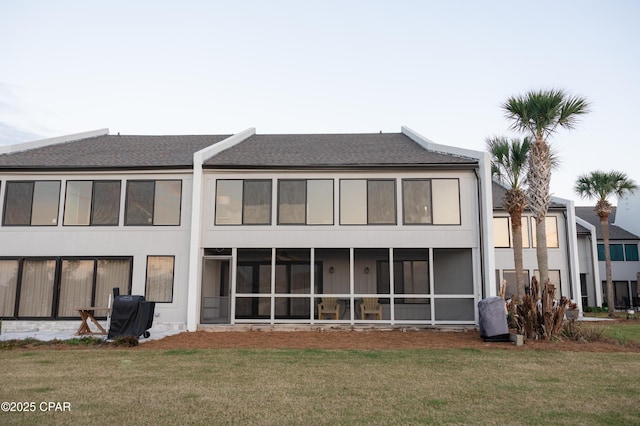 back of house with a shingled roof, a sunroom, and a yard