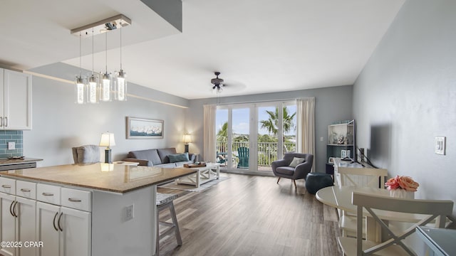 kitchen featuring pendant lighting, a kitchen island, white cabinetry, light stone countertops, and a kitchen breakfast bar