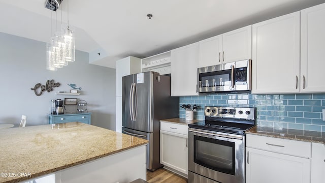 kitchen with decorative light fixtures, white cabinets, light stone countertops, and stainless steel appliances