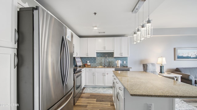 kitchen with appliances with stainless steel finishes, backsplash, hanging light fixtures, white cabinets, and sink