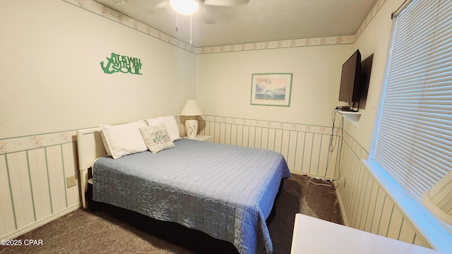 carpeted bedroom featuring a ceiling fan and wainscoting