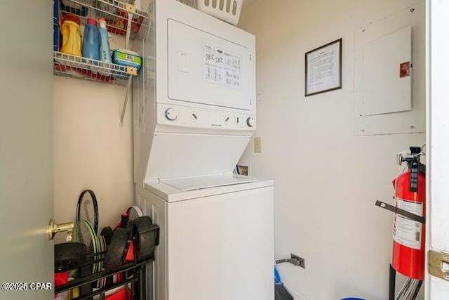 laundry area featuring electric panel, laundry area, and stacked washing maching and dryer