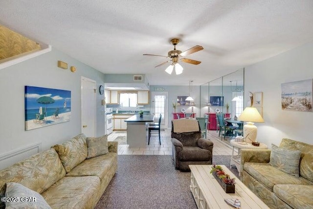 living area featuring ceiling fan, a textured ceiling, and visible vents