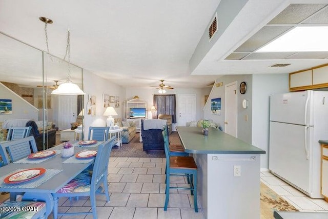 kitchen with visible vents, ceiling fan, open floor plan, a center island, and freestanding refrigerator