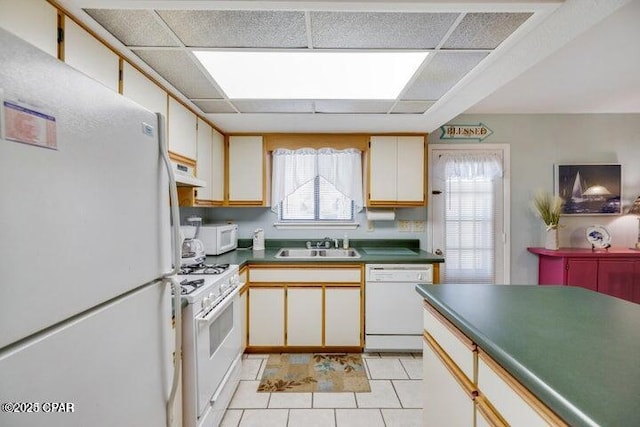 kitchen featuring white appliances, a drop ceiling, a sink, and under cabinet range hood