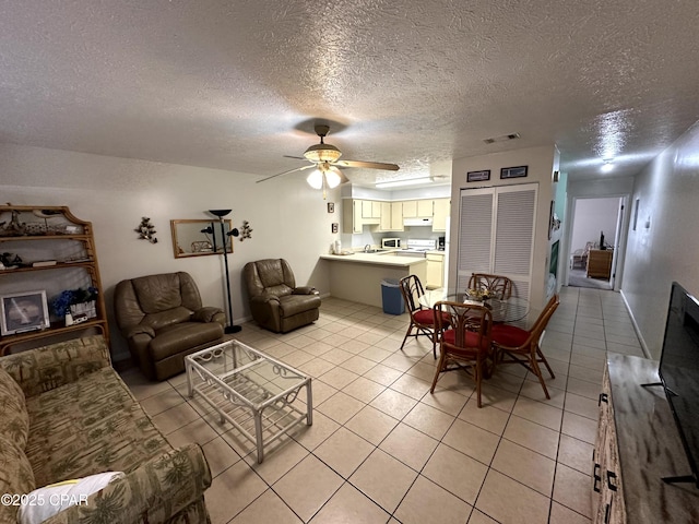 living room featuring ceiling fan, light tile patterned floors, and a textured ceiling