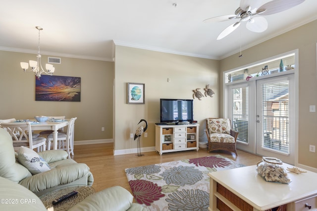 living room with ceiling fan with notable chandelier, crown molding, and light hardwood / wood-style floors