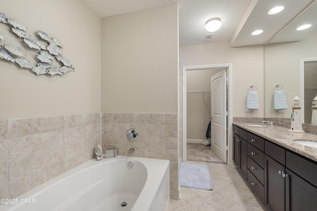 bathroom with a washtub, vanity, and tile patterned flooring