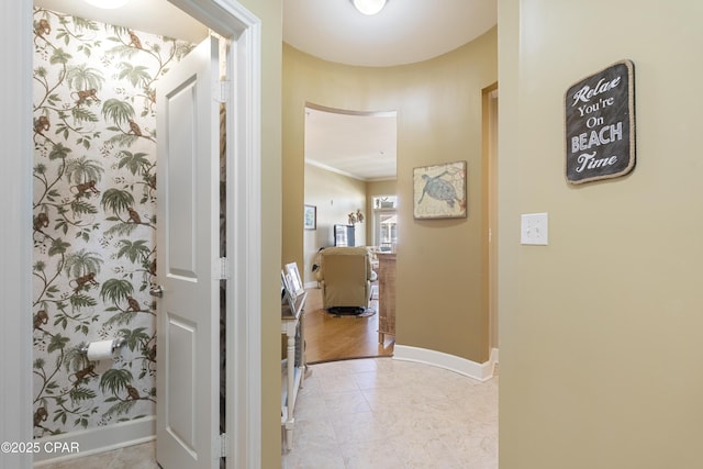 corridor featuring light tile patterned floors and ornamental molding