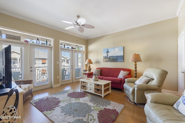 living room with ceiling fan, light hardwood / wood-style flooring, ornamental molding, and a healthy amount of sunlight