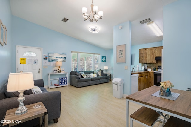 living room featuring vaulted ceiling, sink, a chandelier, and light hardwood / wood-style flooring