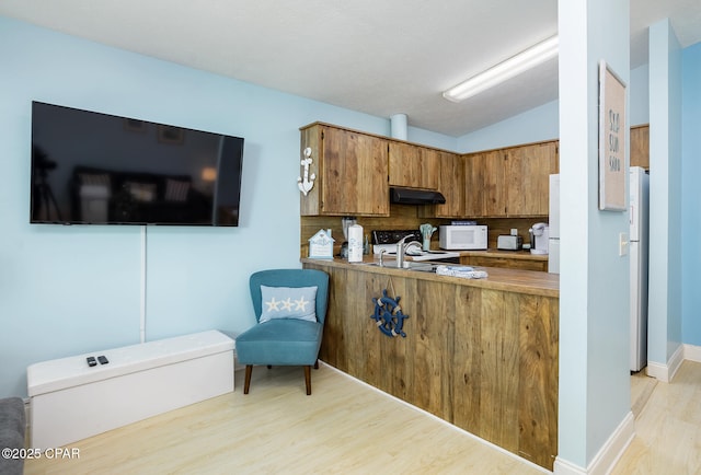 kitchen featuring lofted ceiling, light hardwood / wood-style floors, decorative backsplash, sink, and white appliances