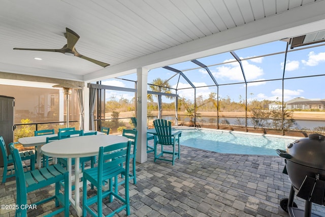 view of pool with a lanai, ceiling fan, a water view, a patio area, and area for grilling