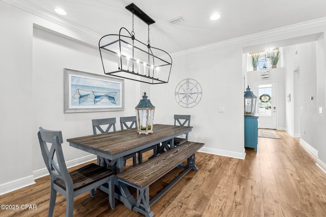 dining room with hardwood / wood-style flooring, crown molding, and a notable chandelier