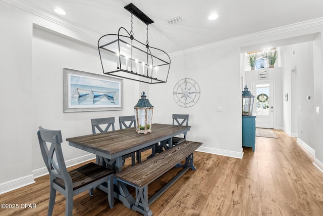 dining area featuring an inviting chandelier, visible vents, light wood-style floors, crown molding, and baseboards