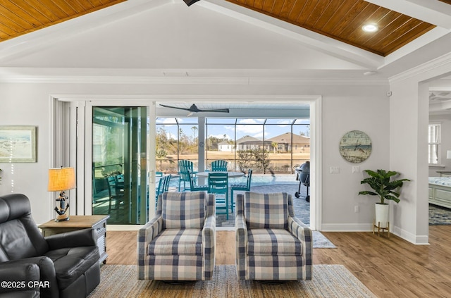 living area with vaulted ceiling with beams, a healthy amount of sunlight, light wood-type flooring, and wooden ceiling