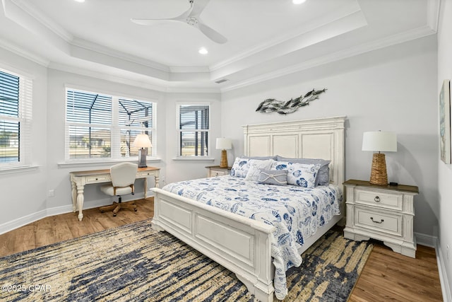 bedroom with a tray ceiling, wood finished floors, and crown molding