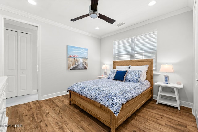 bedroom featuring wood-type flooring, ornamental molding, ceiling fan, and a closet