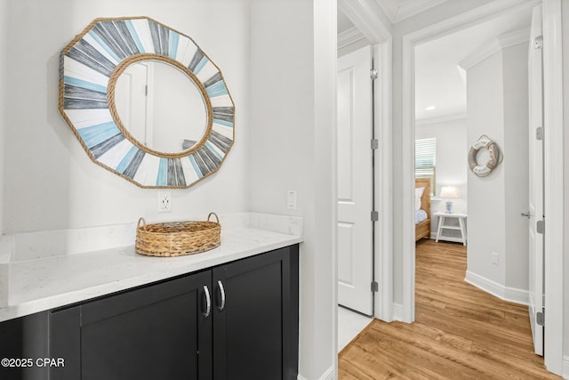 bathroom featuring baseboards, wood finished floors, vanity, and ornamental molding