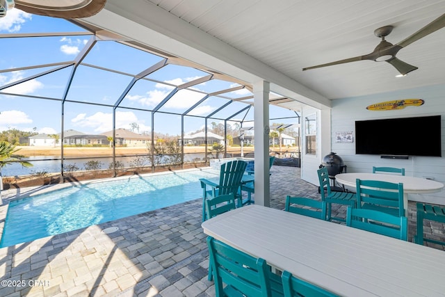 view of swimming pool with a lanai, a patio area, ceiling fan, and a water view