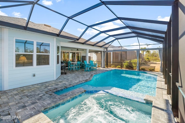 view of pool featuring an in ground hot tub, ceiling fan, glass enclosure, and a patio area