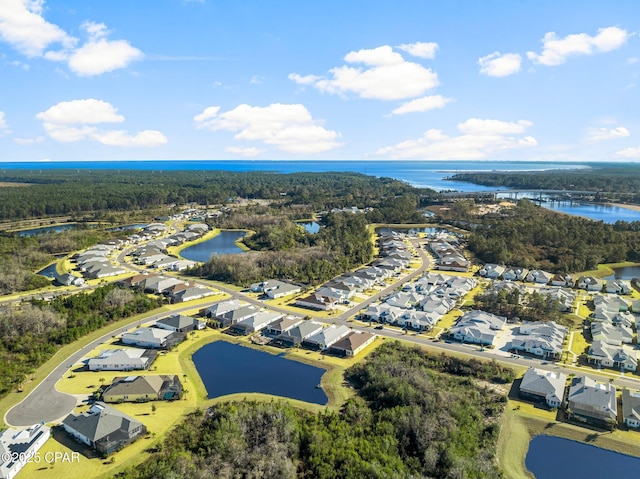 bird's eye view featuring a wooded view, a residential view, and a water view