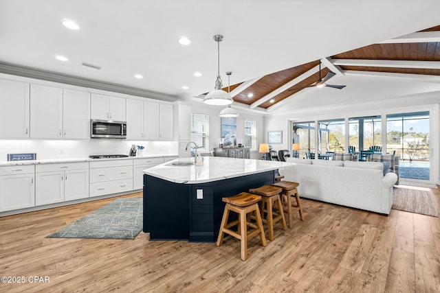 kitchen featuring pendant lighting, wood ceiling, a kitchen island with sink, white cabinets, and decorative backsplash