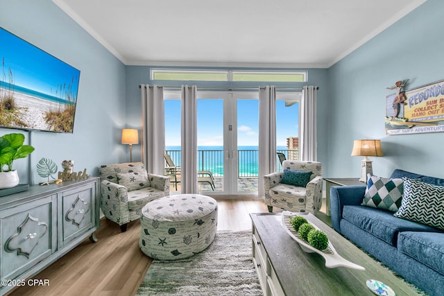 living room with crown molding, light hardwood / wood-style floors, french doors, and a water view